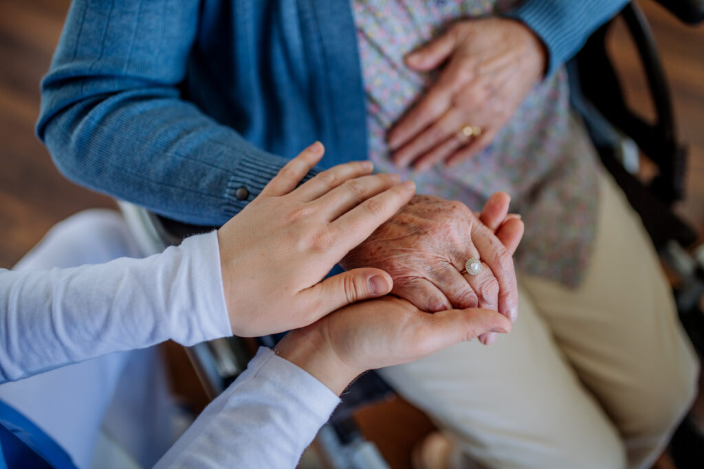 Top view of nurse stroking hands of senior woman.
